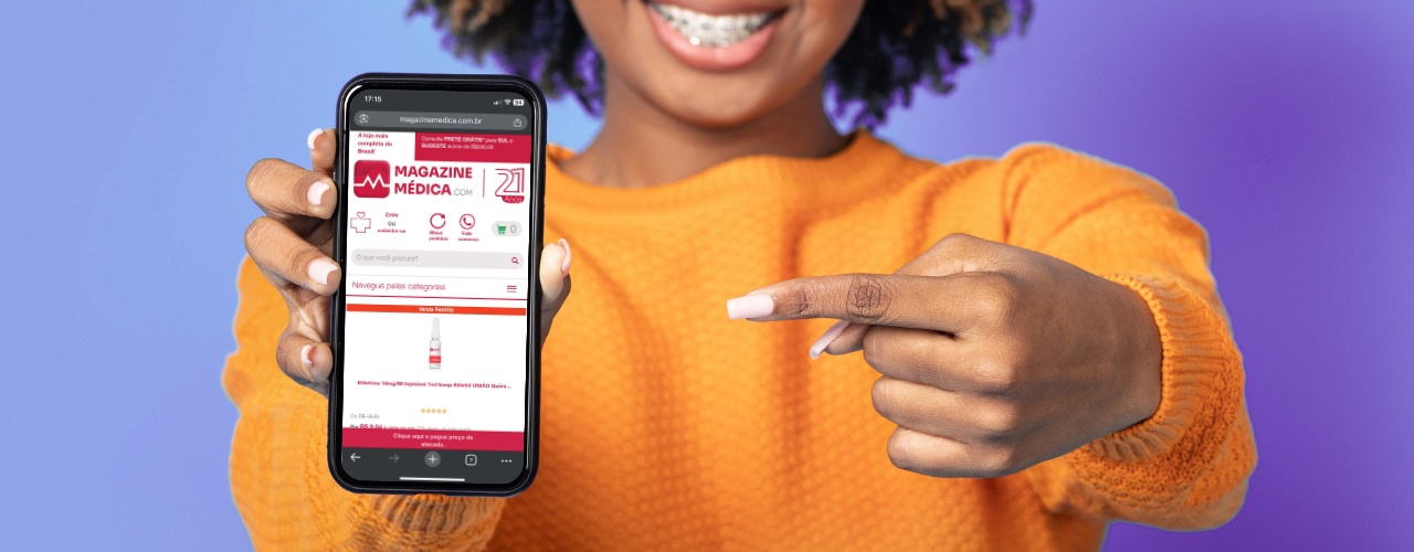 Mulher sorridente segura e aponta para celular com o site da Magazine Médica aberto, loja online de produtos hospitalares com