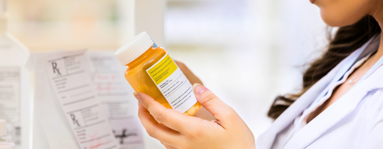 Mulher usando jaleco examina frasco de medicamento com tarja colorida. médico analisa embalagem de medicamento com tarja.