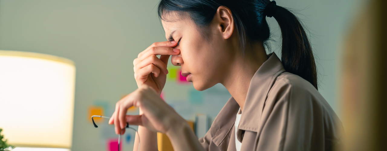 mulher preocupada com a mão nos olhos segurando oculos