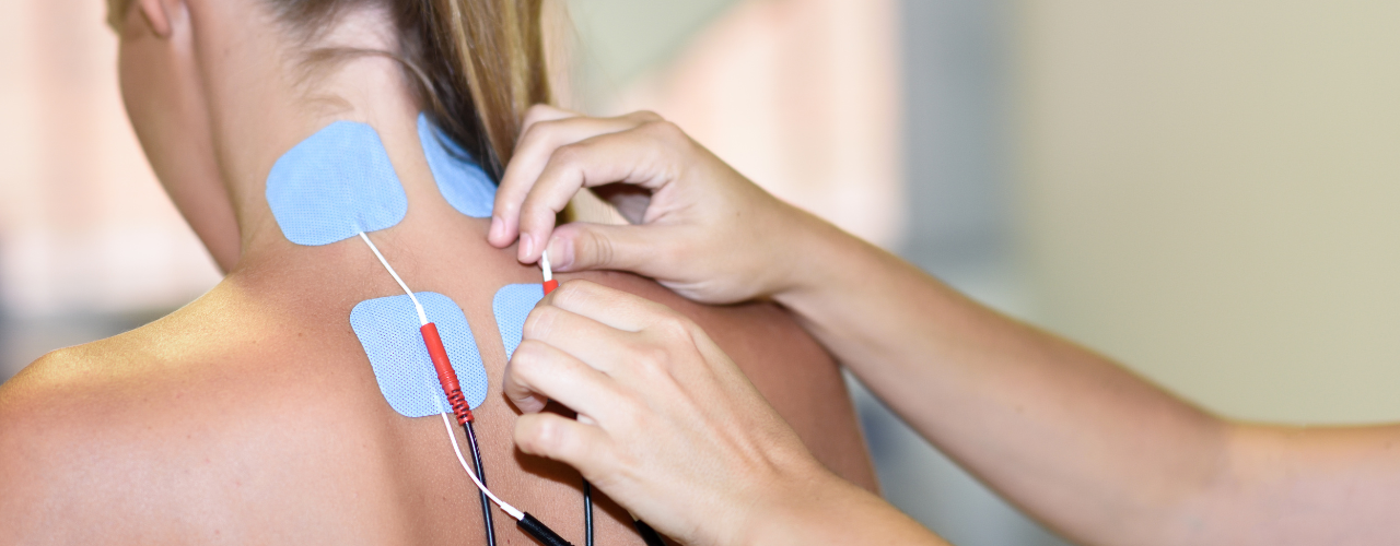 mulher na fisioterapia com quatro eletrodos adesivos na área das costas