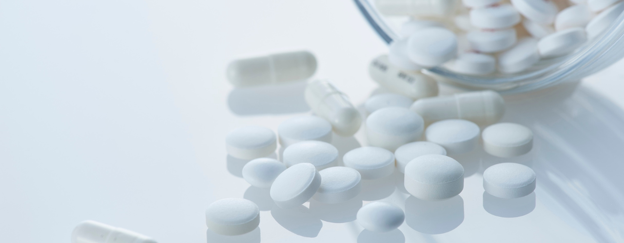 Imagem de comprimidos e cápsulas de medicamentos comumente associados ao tratamento de inflamação, dor e febre.