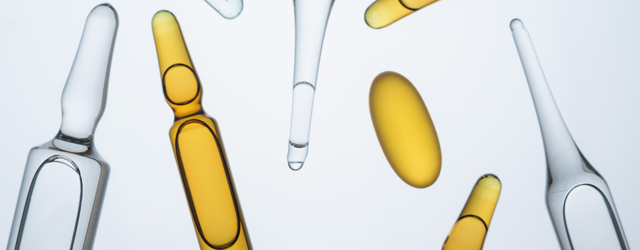 Ampolas transparentes e cápsulas amarelas representando medicamentos utilizados na prática médica.