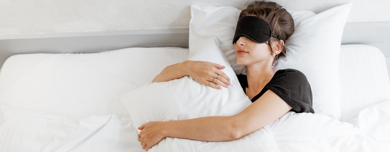 Mulher dormindo com máscara de descanso em seu quarto com cama e lençol branco